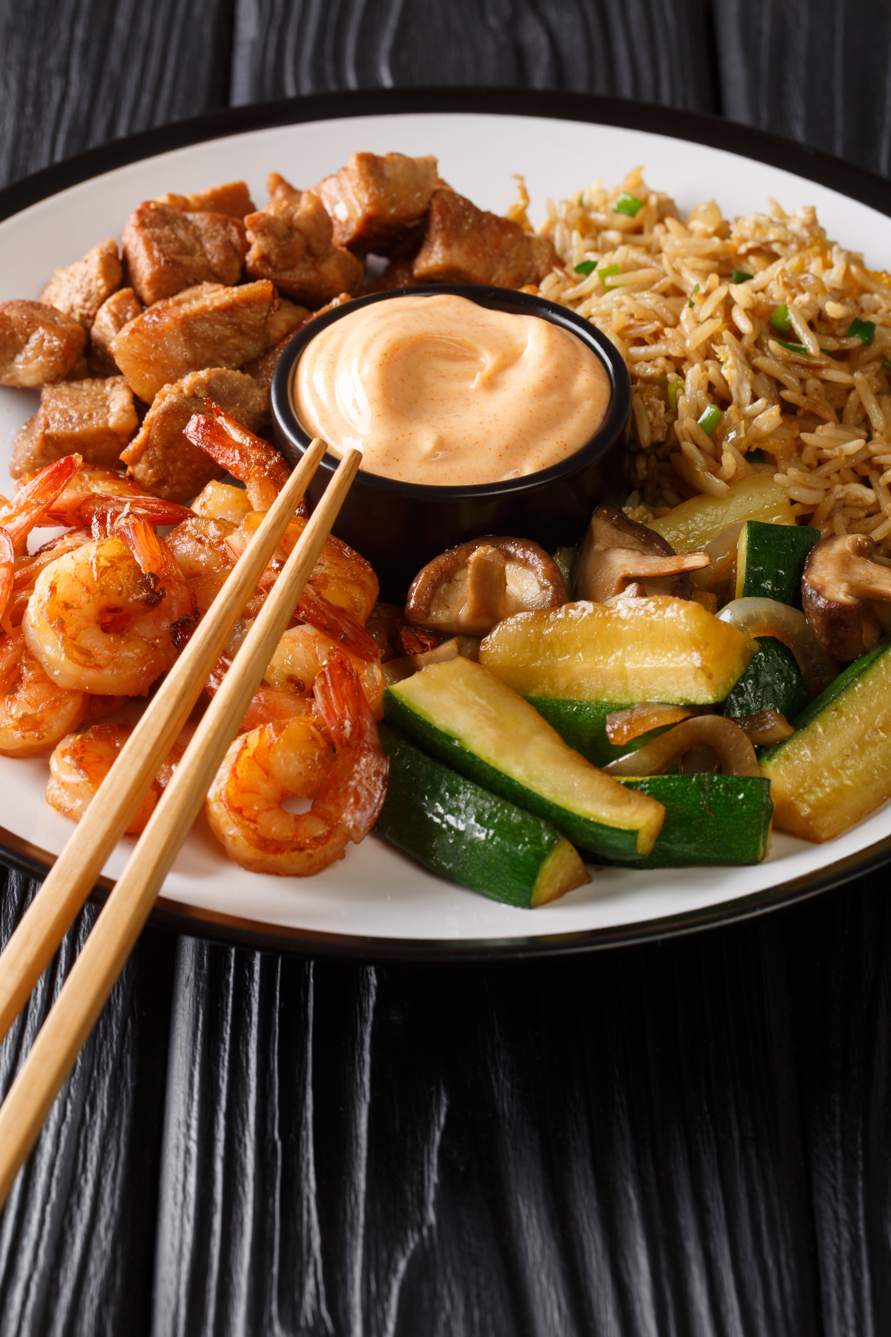 Hibachi fried rice with egg, shrimp, steak and vegetables close-up in a plate. vertical